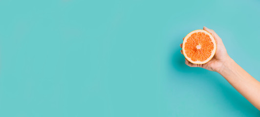 Fresh grapefruit  on pastel background. Hand holding citrus fruit.