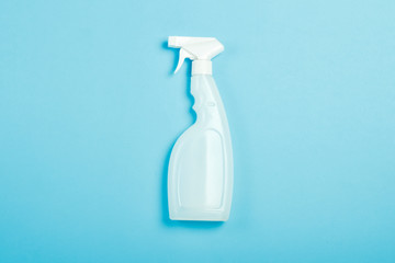 White spray bottle for cleaning or moistening flowers on a blue background. Flat lay, top view.
