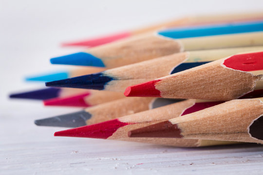 Colored wooden pencils on a white wooden table. Macro. Close up. Side view