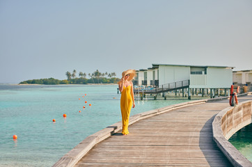 Woman in dress walking on tropical beach boardwalk