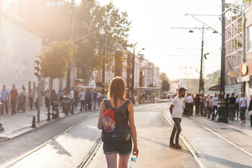 A tourist girl with backpack walks near the great sight in Istanbul on sunset, the mosque of Blue Mosque. Summer vacation, travel.  Scenic panorama of Istanbul with people and landmarks.
