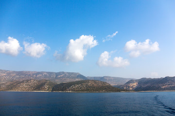 Fototapeta premium Mediterranean sea overlooking the mountains. Aerial top view of sea waves hitting rocks on the beach with turquoise sea water. Amazing rock cliff seascape in the coastline.