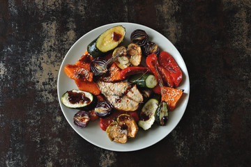 Baked vegetables and fruits with sesame on the plate. Vegan food. Healthy diet. Shabby background. Stylish vegan lunch.