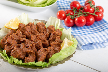 Turkish Food Cig Kofte with lemon, lettuce and parsley on silver plate
