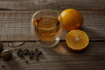 glass of traditional chinese blooming tea, lemons and tea balls on wooden table