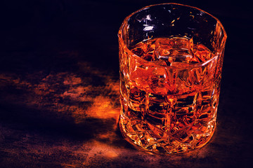 whiskey with ice cubes on wooden background