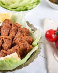 Turkish Food Cig Kofte with lemon, lettuce and parsley on silver plate