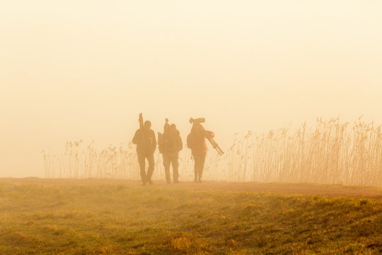 Birdwatchers walking in the fog an early morning