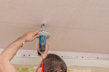 A man holds a power drill in his hands. Make a hole in the ceiling. Repair work in the apartment....
