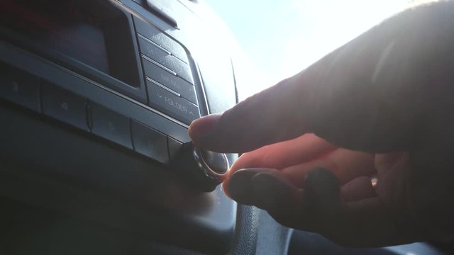 Man turns on the music in the car. Radio in the sun. Man's hand on the car key