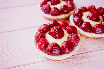 three delicious beautiful bright panna cotta pastries in baskets with berries on a pink wooden...