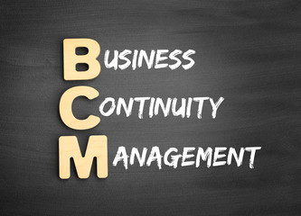 Wooden alphabets building the word BCM - Business Continuity Management acronym on blackboard