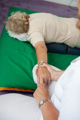 A woman receiving a hand massage lying on a mat