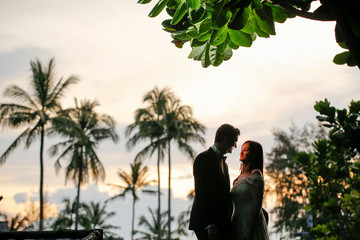 Beutiful wedding couple posing in sunset near beach