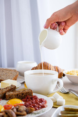 Mug of coffee on the table with English breakfast and croissant