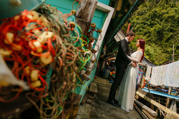 Happy cheerful wedding couple posing on dock near houses