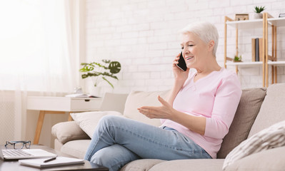 Cheerful senior woman talking with client oh phone