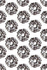 White donut sprinkled with black cookie on white background. Ornament. Seamless pattern