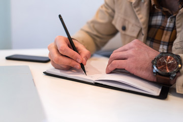 Cropped view of man writing in notebook at table