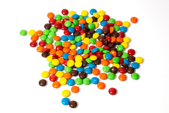 Colorful chocolate MMs in and out of focus on white background