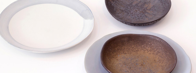 Decorative ceramic plates and gray tablecloth, white table background. Dishes, kitchen, home design, cooking concept. Close-up, copy space, horizontal layout