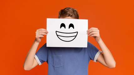 Teenage boy holding paper with smiley face - obrazy, fototapety, plakaty
