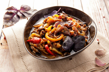Stewed aromatic vegetables in a thick sauce. The traditional dish of Caucasian cuisine. Eggplant, pepper and tomatoes in vegetable oil with garlic and herbs. Ketogenic food. Horizontal view.