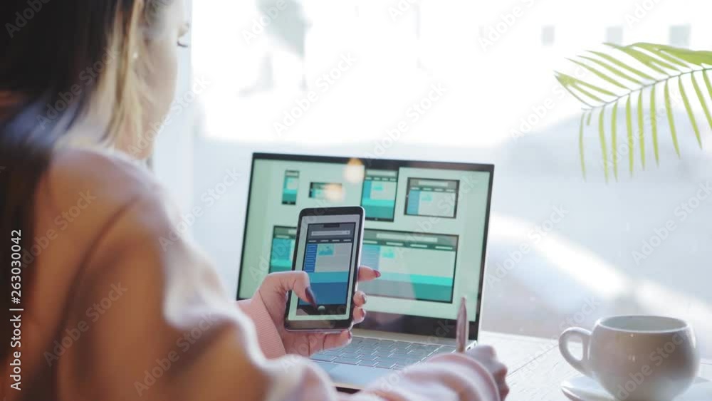 Wall mural over the shoulder view of female website designer creating templates and checking it for different d