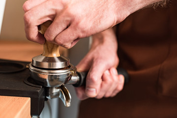 Fototapeta na wymiar Partial view of barista in brown apron preparing coffee