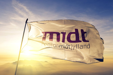 Central Denmark Region flag waving on the top sunrise mist fog