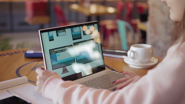 Side view of unrecognizable freelance female website designer creating application design for different devices on laptop while having coffee at table in cafe (ATTN templates designed by ME)