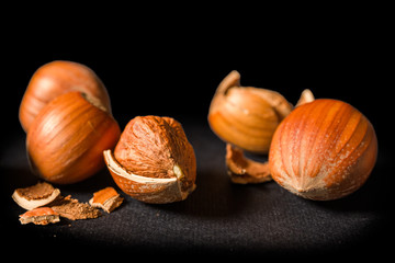 Some shelled hazelnuts with shell fragments around them, isolated on a black background