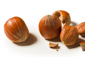 Some shelled hazelnuts with shell fragments around them, isolated on a white background
