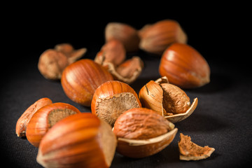 Some shelled hazelnuts with shell fragments around them, isolated on a black background