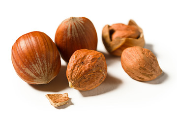 Some shelled hazelnuts with shell fragments around them, isolated on a white background