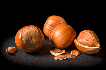 Some shelled hazelnuts with shell fragments around them, isolated on a black background