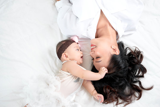 Cute little baby girl and her mother lying on a floor.
