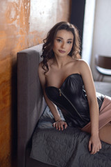 Fototapeta premium Portrait of a young girl in black dress near the bed