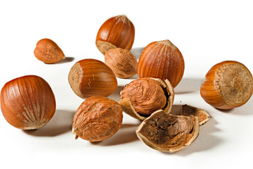 Some shelled hazelnuts with shell fragments around them, isolated on a white background