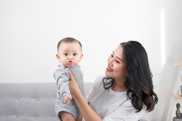 Young mother with her one years old little son dressed in pajamas are relaxing and playing in the...