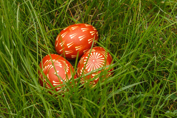 Ukrainian painted easter eggs of red color lie in the grass. Close-up
