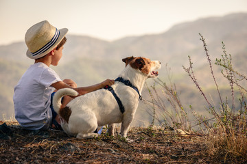 Kid hugging his pet dog looking on mountain view