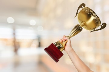 Hand holding golden trophy on blurred background