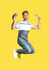 Fototapeta na wymiar Young man jumping with money on color background