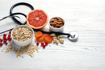 Heart-healthy products and stethoscope on wooden background, space for text