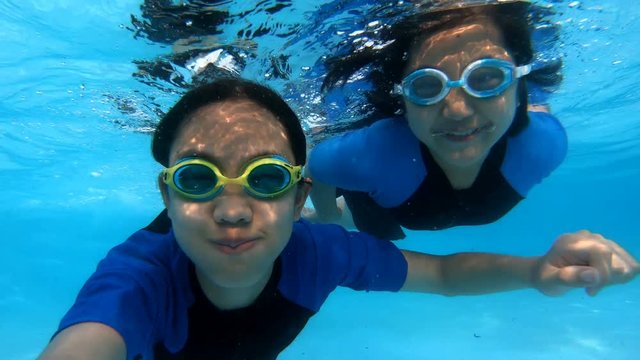 Happy Asian girl diving under the water in the swimming pool