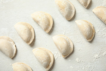 Fototapeta na wymiar Raw dumplings on light background, top view. Process of cooking