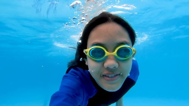 Happy Asian girl diving under the water in the swimming pool
