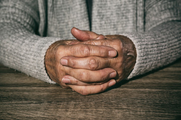 Poor senior woman at table, closeup of hands