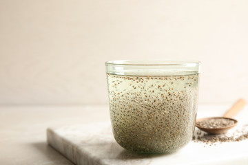 Glass of water with chia seeds and spoon on board, space for text
